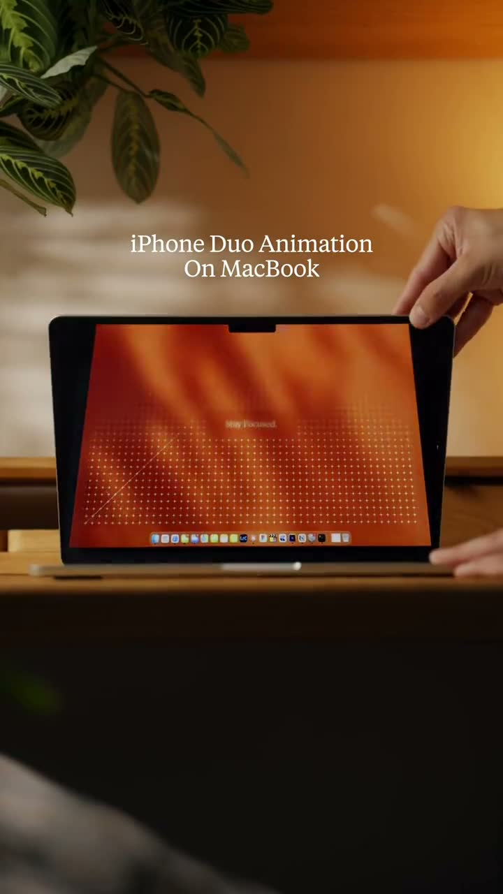 Phone-filmed close-up of a MacBook lid with the desktop folding as the lid closes